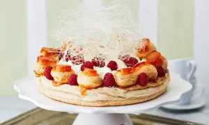 Ein prachtvoller Saint Honoré Kuchen mit Brandmasse-Profiteroles, frischen Himbeeren, Sahne und Karamellfäden.