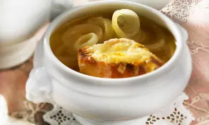 Herzhaftes Zwiebelsuppe Rezept Original: goldbraun überbackenes Brot mit geschmolzenem Käse auf Zwiebelringen in Brühe.
