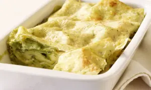 Zucchini-Lasagne mit cremiger Füllung und goldbraunen lasagneplatten in einer weißen Auflaufform.