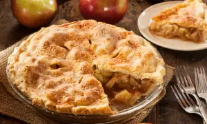 Goldbrauner Apfelkuchen, ein Klassiker der american pie recipe, mit saftiger Füllung und knusprigem Teig. Daneben Äpfel und Gabeln.
