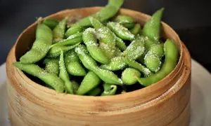 Salzige Edamame-Schoten in einem Bambuskorb. Was ist Edamame? Junge Sojabohnen, eine gesunde und leckere Vorspeise.
