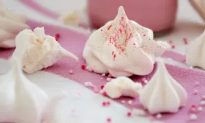 Zarte Baisers, frisch aus dem Ofen, sind nach dem Backen leicht klebrig. Kleine Zuckerperlen zieren die süßen Leckereien.