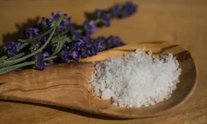 Fleur de Sel, feine Meersalzkristalle, auf einem Olivenholz-Löffel neben Lavendel. Was ist Fleur de Sel? Ein Hauch von Luxus für Ihre Küche.