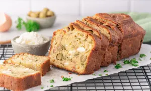 Ein aufgeschnittener, herzhafter Kuchen (cake salé) mit Oliven und Käse, garniert mit Petersilie.