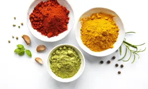 Schalen mit roten, gelben und grünen Gewürzen, Knoblauch und Kräutern – die Zutaten, woher kommt Curry.