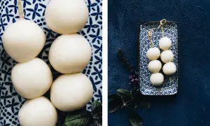 Zwei Spieße mit je fünf runden, weißen Bällchen, die an mitarashi dango erinnern, liegen auf blau-weißen Tellern.