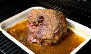 Ein saftiger Lammbraten mit knuspriger Kruste in einer Bratpfanne, bereit für ein köstliches Lammbraten Rezept.