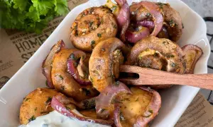 Gefüllte champignons aus dem airfryer mit roten Zwiebeln und Kräutern, serviert mit Dip.