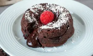 Schokokuchen mit weichem Kern, bestäubt mit Puderzucker und garniert mit einer Himbeere. Der flüssige Kern läuft verführerisch heraus.