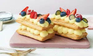 Zwei Mille-feuille-Törtchen mit Vanillecreme und frischen Beeren, bereit zum Genießen.