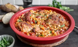 Herzhaftes Cassoulet Rezept in roter Auflaufform mit Hähnchen, Wurst und weißen Bohnen, garniert mit Petersilie.