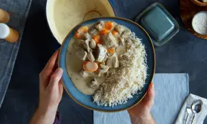 Ein Teller mit cremigem Blanquette de veau, Pilzen und Karotten, serviert mit Reis.