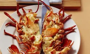 Zwei Hälften Hummer Thermidor, überbacken mit cremiger Sauce und Gewürzen, auf einem Teller angerichtet.
