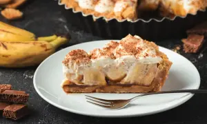 Ein Stück Banoffee Pie mit Bananen, Karamell und Sahne, bestreut mit Kakaopulver. Perfekt für Ihr Banoffee Pie Rezept!