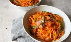 Zwei Schüsseln mit leckerem Spaghetti Napolitan, garniert mit Paprika und Wurst.