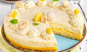 Ein köstlicher Ananas Kokos Kuchen, verziert mit Kokosraspeln, Sahnetuffs, Ananasstücken und Minze.