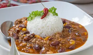 Herzhaftes Chili con Carne mit Reis, garniert mit Petersilie und einer getrockneten Chili.