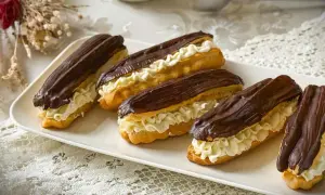 Fünf köstliche Éclairs mit Schokoladenglasur und Sahnefüllung auf einer weißen Platte, perfekt für ein Éclair-Rezept.