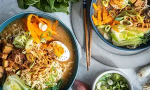 Zwei Schalen mit dampfendem, **vegetarischem Ramen**. Nudeln, Karottenstreifen, Pak Choi, Tofuwürfel und ein halbes Ei in herzhafter Brühe.