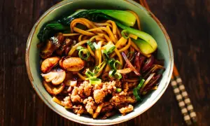 Schüssel mit Yaki Udon Nudeln, Hackfleisch, Pilzen, Pak Choi und Frühlingszwiebeln.