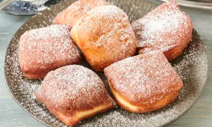 Leckere, goldbraune Beignets, bestäubt mit Puderzucker. Dieses Beignets Rezept ist ein Genuss!