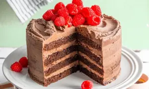 Saftige Mokkatorte mit Buttercreme, dekoriert mit frischen Himbeeren. Ein Stück ist herausgeschnitten, um die vielen Schichten zu zeigen.
