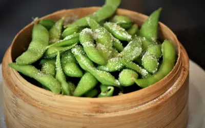 Salzige Edamame-Schoten in einem Bambuskorb. Was ist Edamame? Junge Sojabohnen, eine gesunde und leckere Vorspeise.