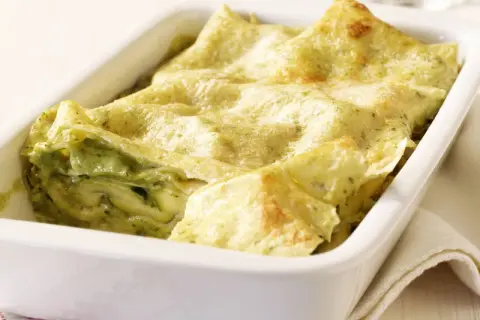 Zucchini-Lasagne mit cremiger Füllung und goldbraunen lasagneplatten in einer weißen Auflaufform.