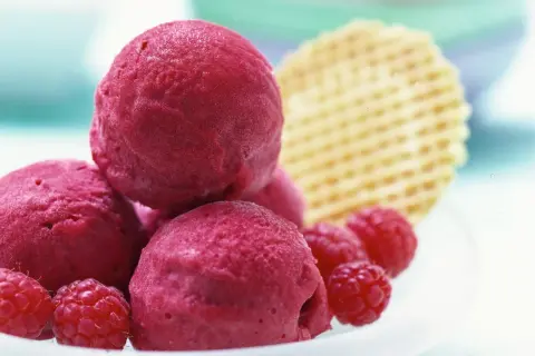 Himbeer Sorbet Kugeln mit frischen Himbeeren und Waffel. Ein erfrischender Genuss für heiße Tage.