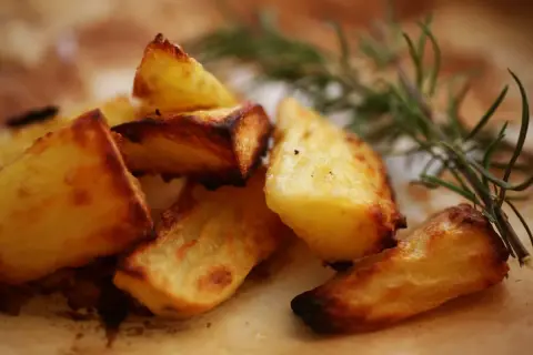 Knusprige Kartoffeln aus dem Ofen, goldbraun und mit Rosmarin verfeinert, verlocken zum Zugreifen.