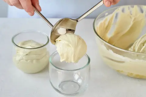 Eine Portion cremiger Pistazienmousse wird mit einem Löffel in ein Glas gegeben.