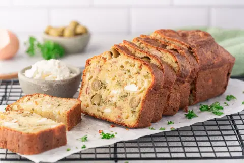 Ein aufgeschnittener, herzhafter Kuchen (cake salé) mit Oliven und Käse, garniert mit Petersilie.