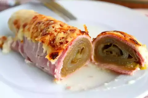 Endives au jambon, überbacken mit Käse, auf einem Teller serviert. Ein köstliches Gericht, das zum Genießen einlädt.