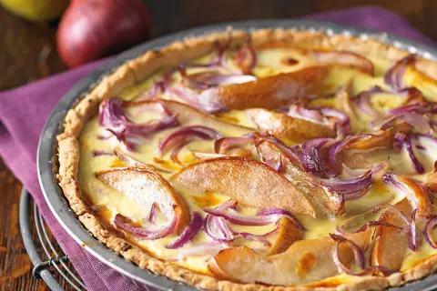 Herzhafte birnen quiche mit roten Zwiebeln und cremigem Guss, appetitlich in einer Metallform serviert.