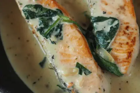 Saftiger Lachs mit Spinat in cremiger Sauce, garniert mit Tomatenstücken. Ein köstliches Gericht, das Lust auf mehr macht.