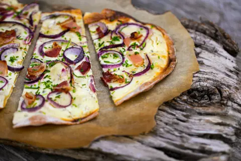 Flammkuchen mit Zwiebeln, Speck und Schnittlauch. Ein klassisches rezept flammkuchen belag, das immer schmeckt.