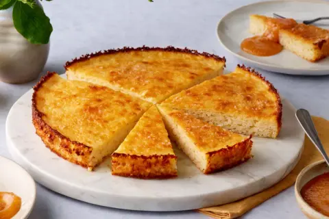 Goldbrauner Reiskuchen, aufgeschnitten und mit Apfelmus serviert. Ein köstliches Reiskuchen Rezept zum Nachbacken.