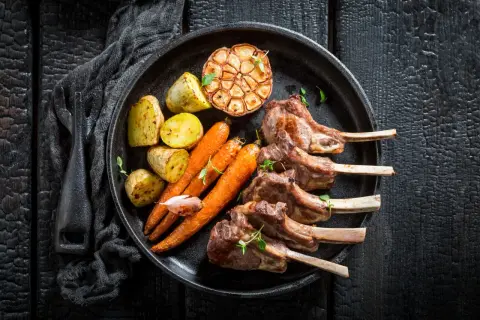 Saftiges Lammkarree mit Rosmarinkartoffeln, Karotten und geröstetem Knoblauch – das beste Rezept für einen Festtagsschmaus.