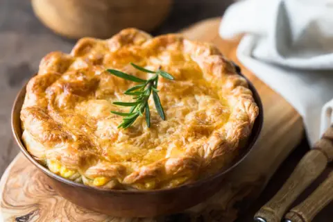 Goldbrauner, knuspriger Pot Pie mit Rosmarinzweig, bereit zum Servieren.