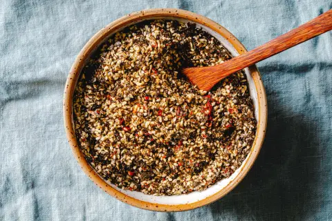 Schale mit selbstgemachtem Furikake, einer Mischung aus geröstetem Sesam, Algen und Chili. Ein Holzspatel liegt darin.