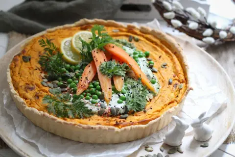 Herzhafte quiche mit pfifferlingen, garniert mit Erbsen, Karotten, Zitrone und Kräutern. Ein frühlingshafter Genuss!