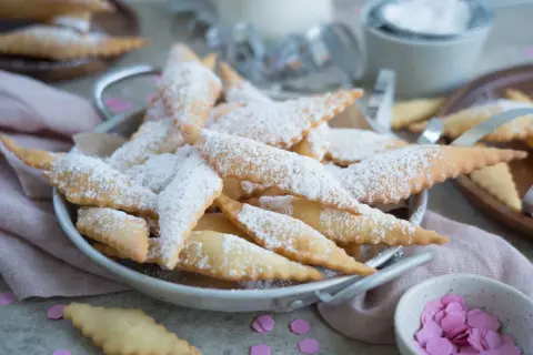 Leckere, knusprige Mutzen, bestäubt mit Puderzucker, warten auf Genießer. Was sind Mutzen? Diese frittierten Teigteilchen sind ein süßer Genuss!