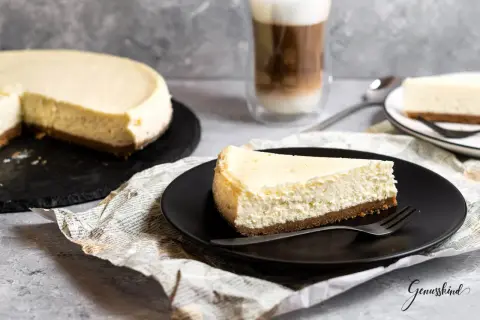 Ein Stück cremiger American Cheesecake, perfekt für das original american cheesecake rezept. Dazu ein Latte Macchiato.
