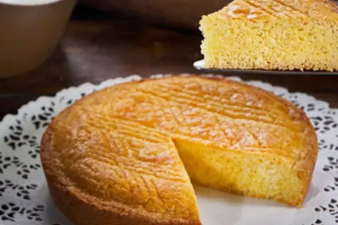 Ein goldbraunes Gateau Breton mit einem Stück auf einem Tortenheber.