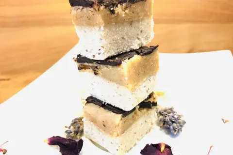 Gestapelte Scheiben Millionaire Shortbread mit Schokoladenglasur, dekoriert mit Lavendel und Blütenblättern.