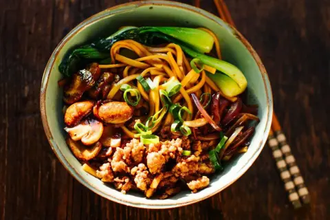 Schüssel mit Yaki Udon Nudeln, Hackfleisch, Pilzen, Pak Choi und Frühlingszwiebeln.