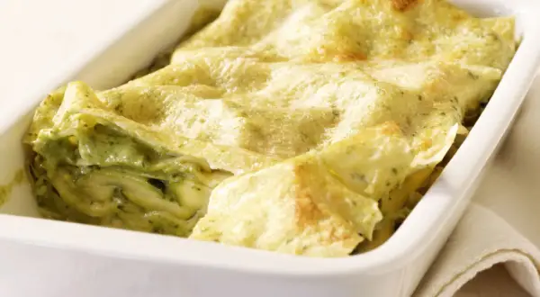 Zucchini-Lasagne mit cremiger Füllung und goldbraunen lasagneplatten in einer weißen Auflaufform.