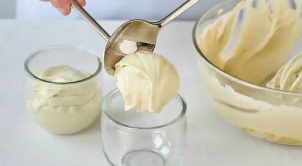 Eine Portion cremiger Pistazienmousse wird mit einem Löffel in ein Glas gegeben.