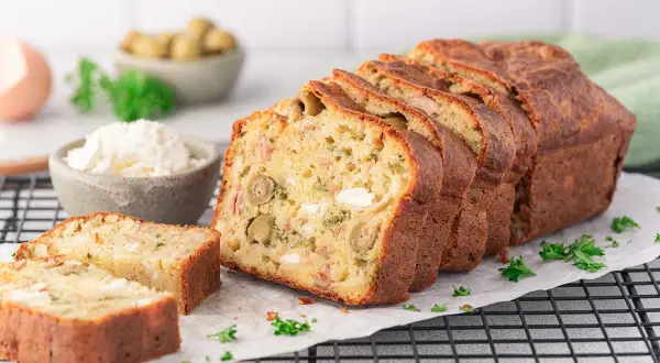 Ein aufgeschnittener, herzhafter Kuchen (cake salé) mit Oliven und Käse, garniert mit Petersilie.