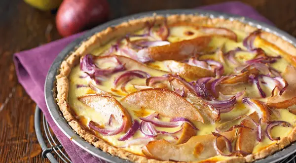 Herzhafte birnen quiche mit roten Zwiebeln und cremigem Guss, appetitlich in einer Metallform serviert.